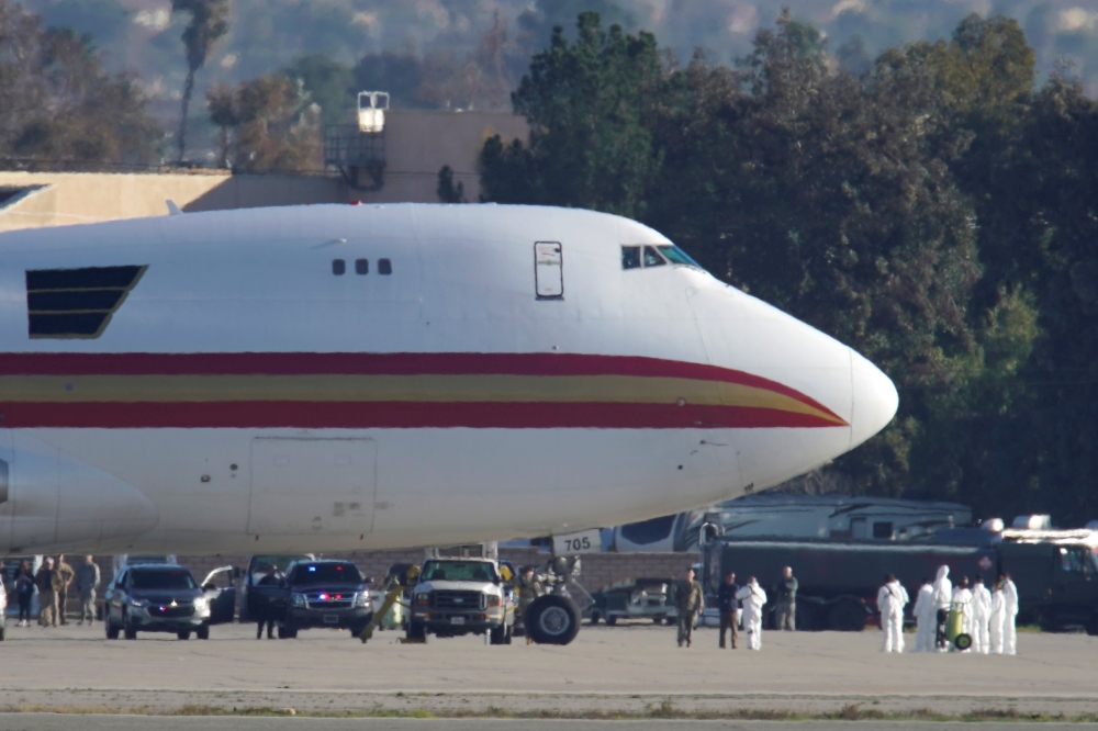 Personnel in protective clothing approach an aircraft, chartered by the U.S. State Department to evacuate government employees and other Americans from the novel coronavirus threat in the Chinese city of Wuhan, after it arrived at March Air Reserve Base i