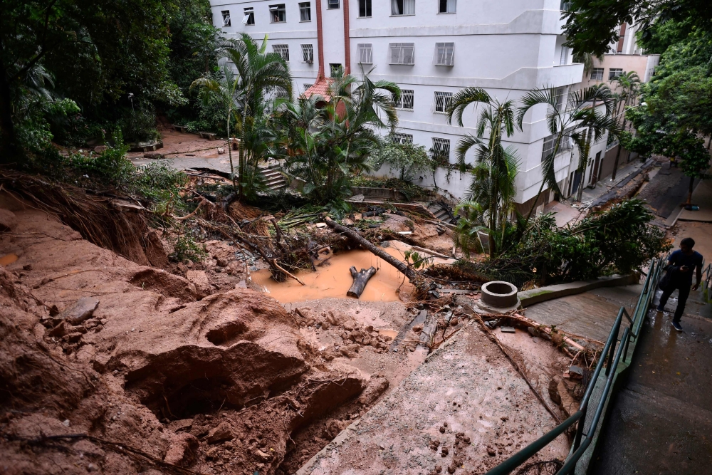 A local walks up stairs next to an area covered with mud and water after heavy rains at the Sao Pedro neighborhood, in Belo Horizonte, state of Minas Gerais, Brazil, on January 29, 2020. The death toll from days of intense storms and flooding in southeast
