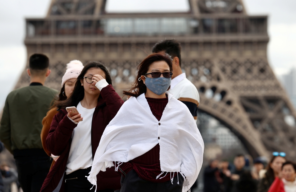 A woman wears a protective mask in light of the coronavirus outbreak in China as she walks at the Trocadero esplanade in front of the Eiffel Tower in Paris, France, February 1, 2020. REUTERS/Gonzalo Fuentes