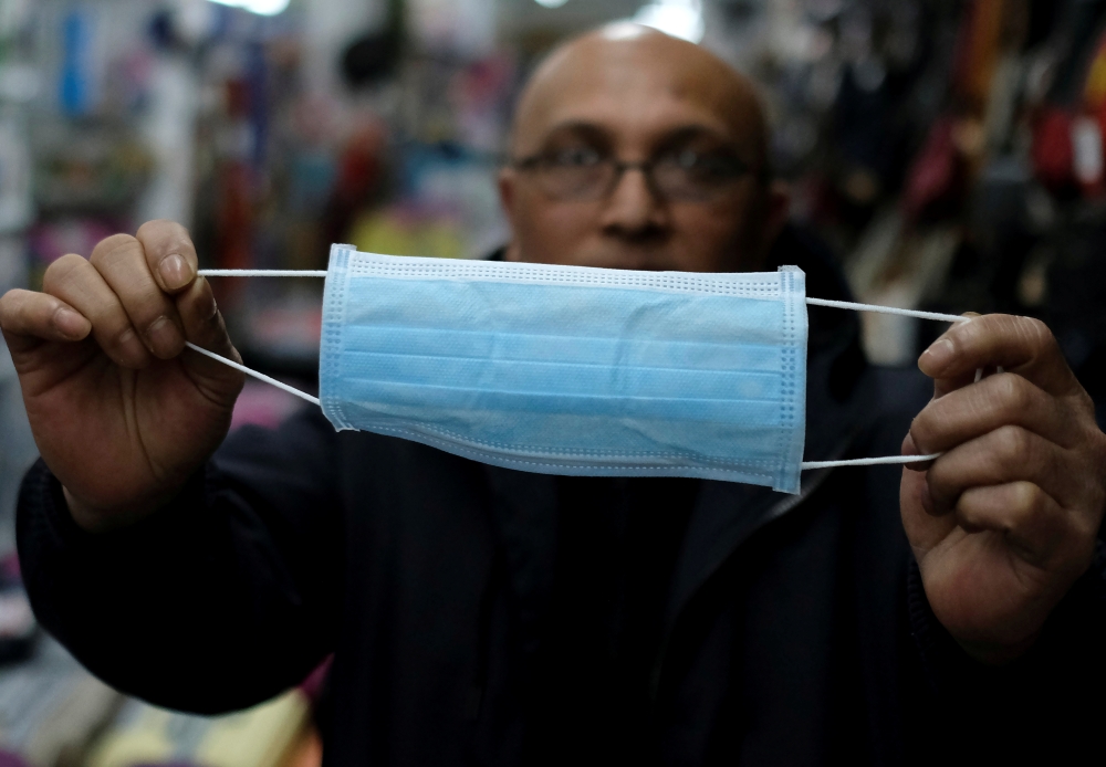 A Pakistani vendor holds a paper mask for sale at his shop, as pharmacies are running out of face masks due to the large demand from Asian people, who buy and send them to relatives in their countries of origin, amid the new coronavirus outbreak, in Barce