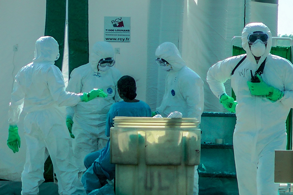 A Sri Lankan student (C) who was evacuated from the Chinese city of Wuhan is checked by medical staff wearing protective gear at Mattala Rajapaksa International Airport in Mattala on February 1, 2020.  AFP