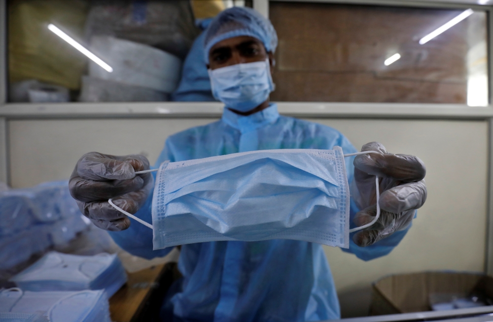 A worker displays a face mask before packing it inside a factory on the outskirts of Ahmedabad, India, February 3, 2020.( REUTERS/Amit Dave)