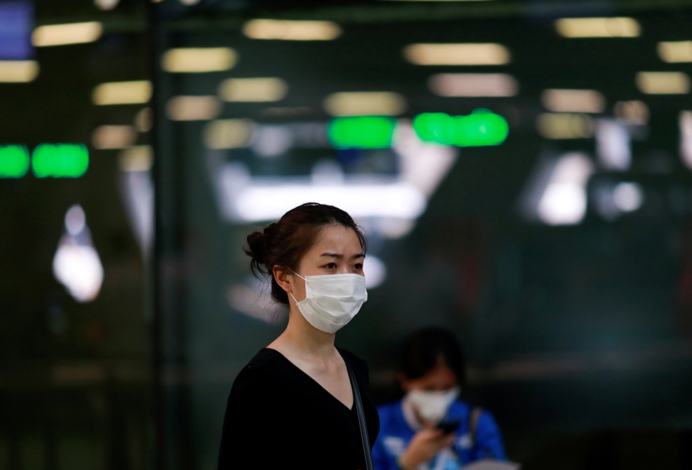 FILE PHOTO: A tourist wears a mask to prevent the spread of the new coronavirus as she arrives at the Suvarnabhumi Airport in Bangkok, Thailand February 3, 2020. REUTERS/Soe Zeya Tun/File Photo