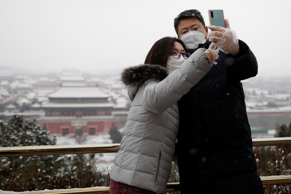 People wearing face masks take selfies at Jingshan Park, as the country is hit by an outbreak of the new coronavirus, in Beijing, China February 5, 2020. REUTERS/Carlos Garcia Rawlins