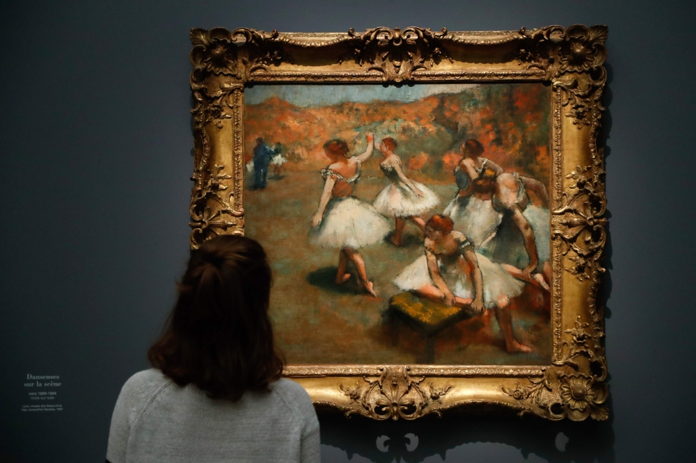 A person looks at the painting Dancers on stage made around 1889 and 1894 by Edgar Degas, during the exhibition Degas at the Opera at the Museum of Orsay, Paris, on September 20, 2019. AFP / Francois Guillot