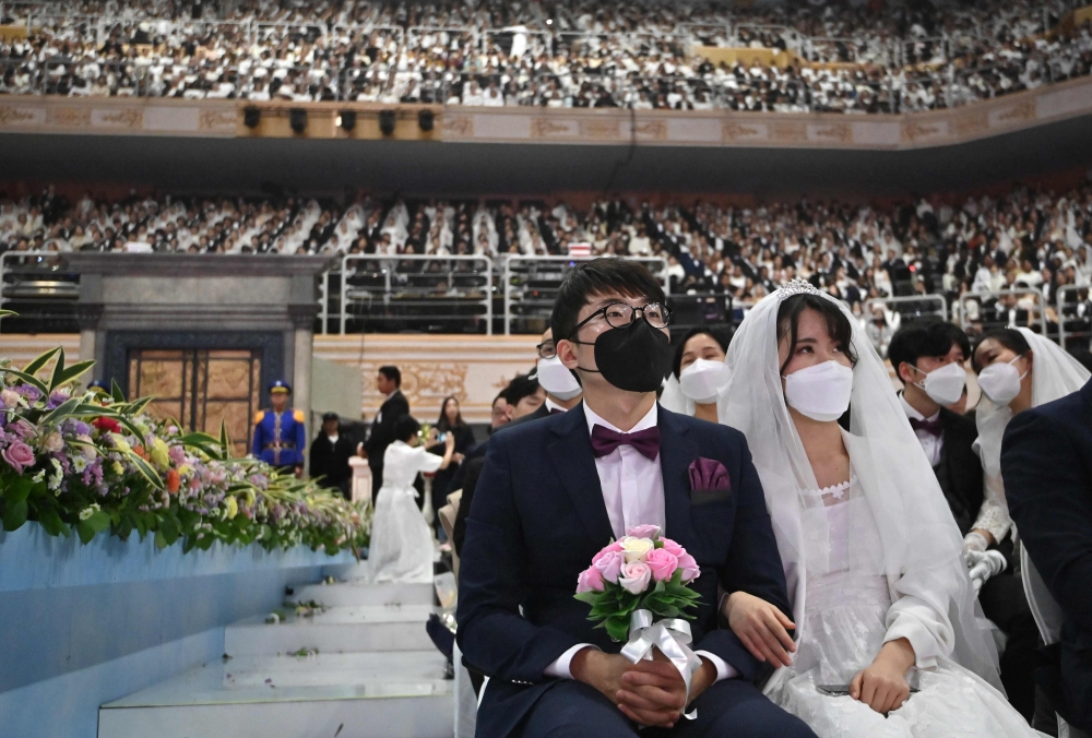 Couples wearing protective face masks attend a mass wedding ceremony organised by the Unification Church at Cheongshim Peace World Center in Gapyeong, South Korea, on February 7, 2020. AFP / Jung Yeon-je
 