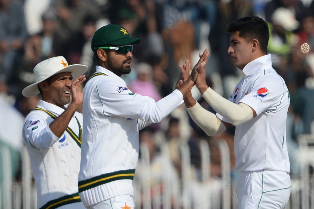 Pakistan's bowler Naseem Shah (R) celebrates with teammates Babar Azam (C) and Asad Shafiq after the dismissal of Bangladesh's Saif Hassan (unseen) during the third day of the first cricket Test match between Pakistan and Bangladesh at the Rawalpindi Cric