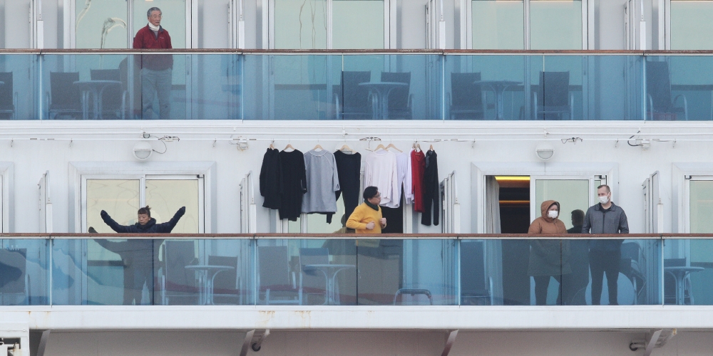Passengers stand on balconies onboard the quarantined Diamond Princess cruise ship at Daikoku Pier Cruise Terminal in Yokohama on February 7, 2020. Another 41 people on a cruise ship quarantined off Japan have the new coronavirus, the country's health min