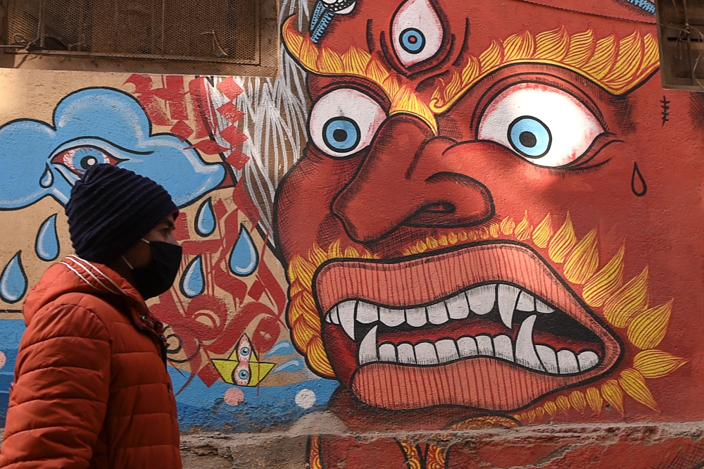 A resident wearing a protective facemask walks at the Patan Durbar Square area in Kathmandu on February 10, 2020. AFP / Prakash Mathema
 