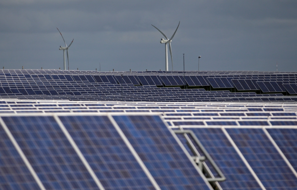 A solar power plant is seen past wind turbines in Canino central Italy, April 27, 2016. Reuters /  Max Rossi
