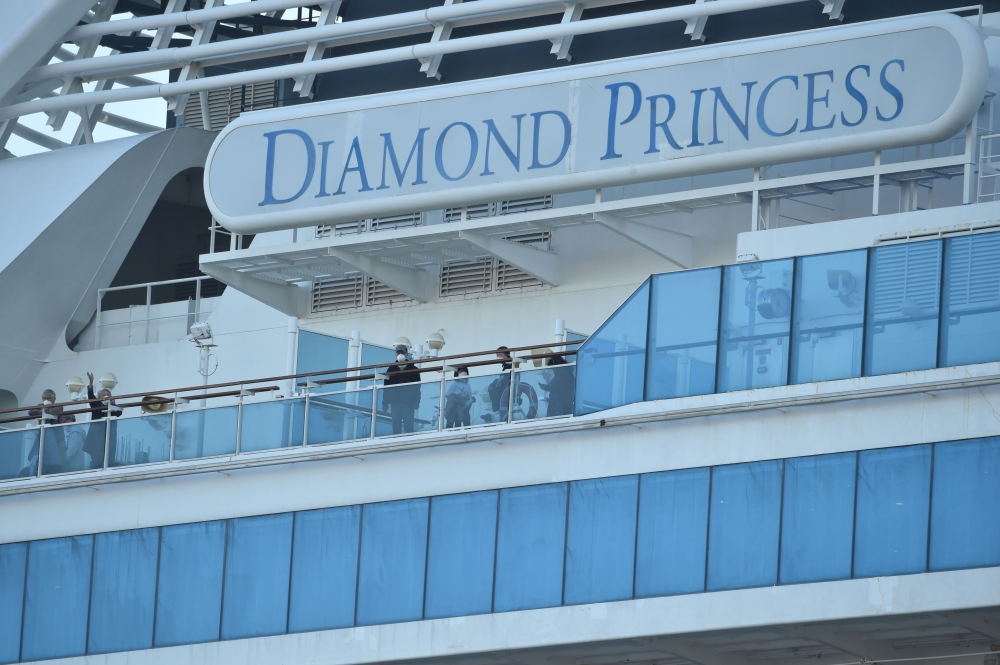 Passengers are seen on the deck of the Diamond Princess cruise ship, with around 3,600 people quarantined onboard due to fears of the new coronavirus, at the Daikaku Pier Cruise Terminal in Yokohama port on February 13, 2020. AFP / Kazuhiro Nogi
 