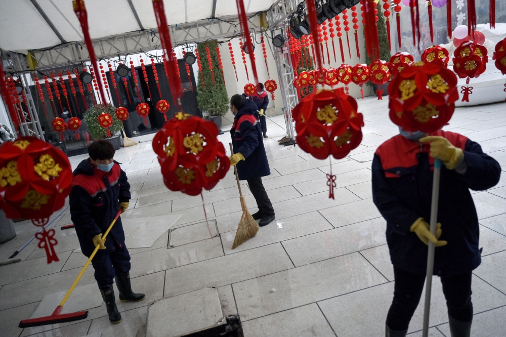 Workers wearing face masks clean the ground of a food court amid snowfall, following an outbreak of the novel coronavirus in the country, on Valentine's Day at the Sanlitun shopping area in Beijing, China February 14, 2020. (REUTERS/Tingshu Wang)