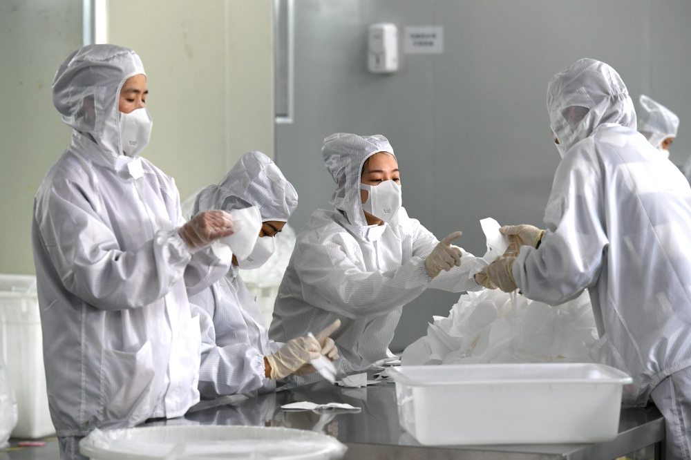 Employees work on a production line manufacturing face masks at a factory, as the country is hit by an outbreak of the novel coronavirus, in Fuzhou, Fujian province, China February 15, 2020. (cnsphoto via REUTERS)