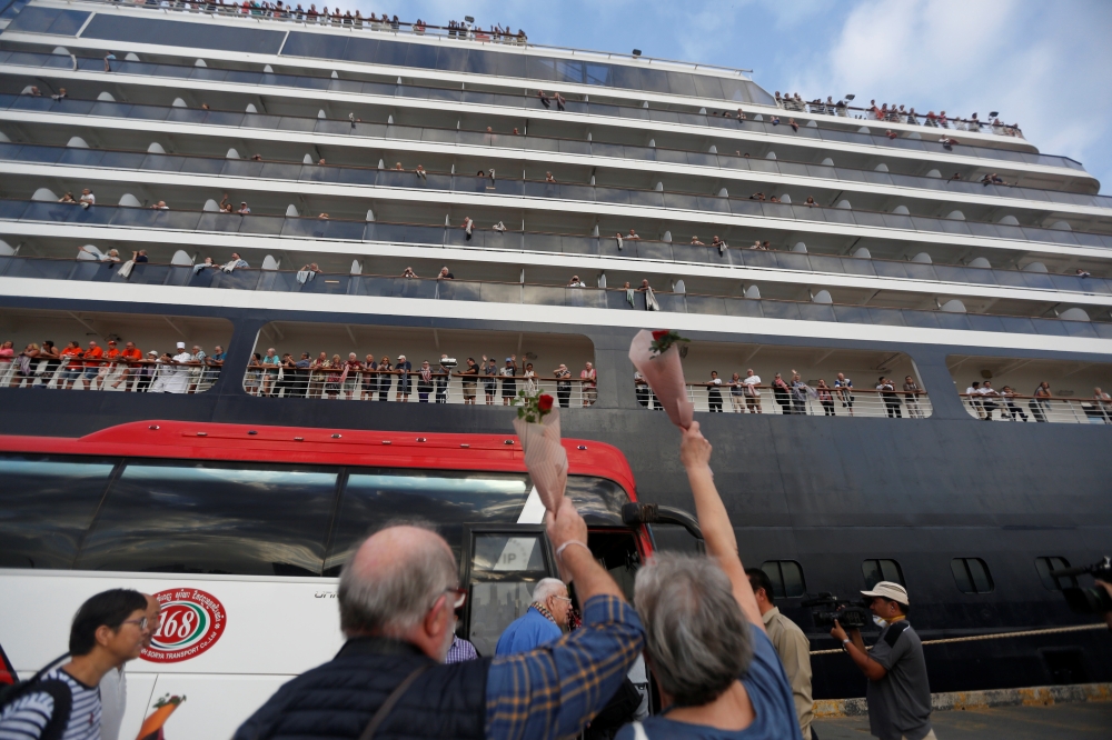 Passengers wave their hands after they depart from MS Westerdam, a cruise ship that spent two weeks at sea after being turned away by five countries over fears that someone aboard might have the coronavirus, as it docks in Sihanoukville, Cambodia Februar