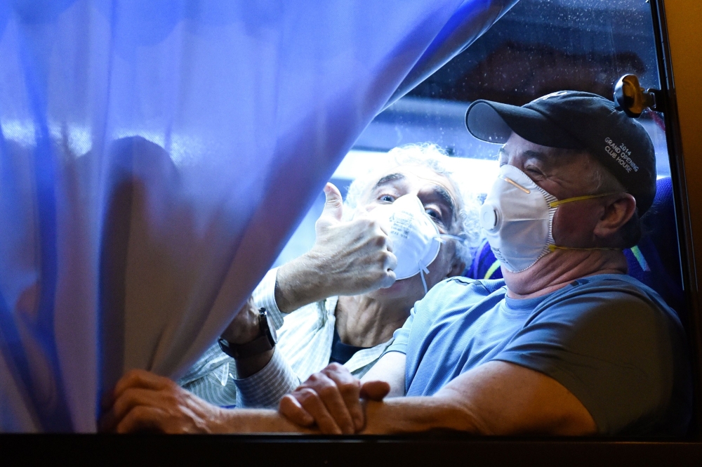 A US passenger thumbs up to reporters while arriving at the Haneda Airport, in Tokyo on February 17, 2020 after disembarking in Yokohama from the Diamond Princess cruise ship, where people are quarantined onboard due to fears of the new COVID-19 coronavir