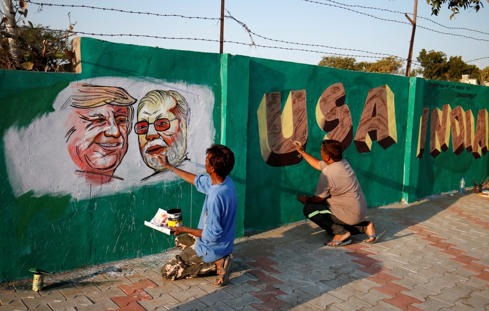 A man applies finishing touches to paintings of US President Donald Trump and India's Prime Minister Narendra Modi on a wall as part of beautification along a route that Trump and Modi will be taking during Trump's upcoming visit, in Ahmedabad, India, Feb
