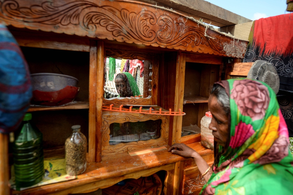 In this photograph taken on November 11, 2019, Bangladeshi mother-of-four Mosammat Rashida, whose husband was killed by a Bengal tiger a decade ago while he was collecting honey, stands next to a mirror at her house in Shyamnagar. AFP / Munir Uz Zaman 