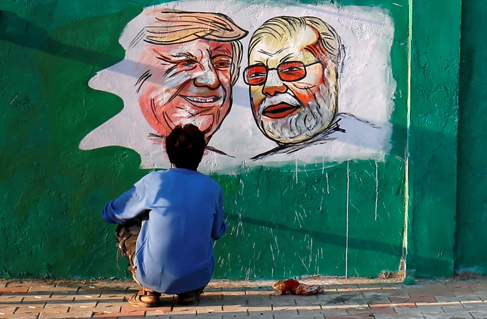  A man applies finishing touches to paintings of U.S. President Donald Trump and India's Prime Minister Narendra Modi on a wall as part of a beautification along a route that Trump and Modi will be taking during Trump's upcoming visit, in Ahmedabad, India