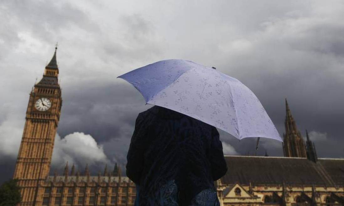 A woman looks towards dark clouds over the Houses of Parliament in central London, August 11, 2014. Reuters / Luke MacGregor