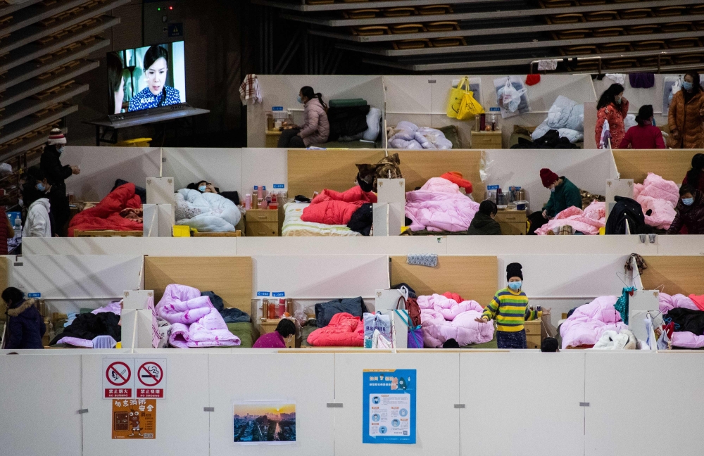 This photo taken on February 18, 2020 shows patients with mild symptoms of the COVID-19 coronavirus resting at night in the temporary Fangcai Hospital set up in a sports stadium in Wuhan, in China's central Hubei province. / AFP / STR
