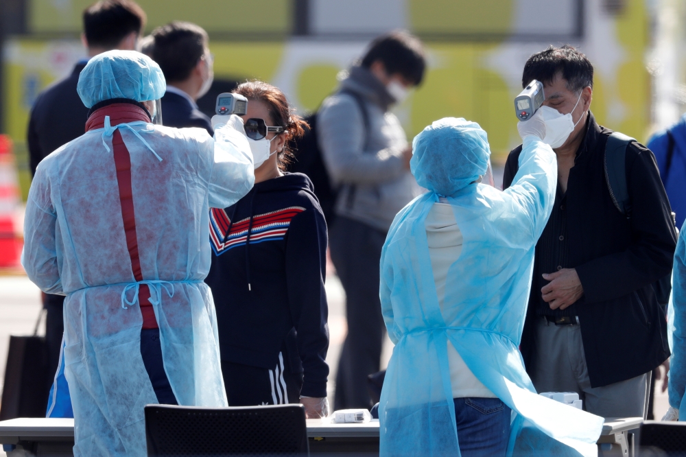  Passengers wearing masks have their body temperatures taken after leaving the coronavirus-hit cruise ship Diamond Princess at Daikoku Pier Cruise Terminal in Yokohama, south of Tokyo, Japan February 21, 2020. REUTERS/Kim Kyung-Hoon 