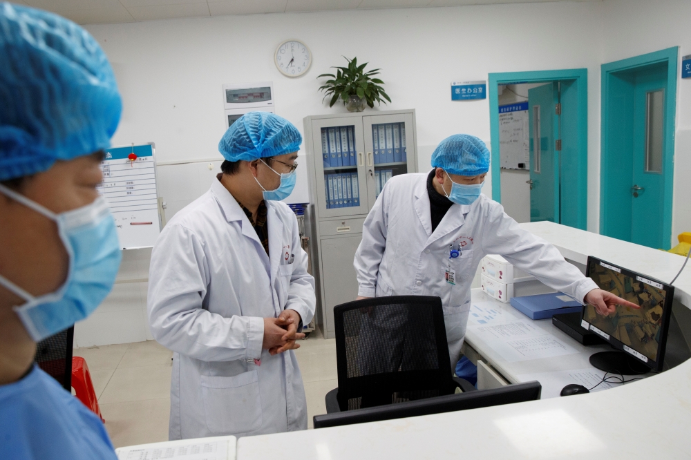 Doctors look at a screen that shows the ward where patients who are infected with the coronavirus are treated at the First People's Hospital in Yueyang, Hunan Province, near the border to Hubei Province, which is under partial lockdown after an outbreak o