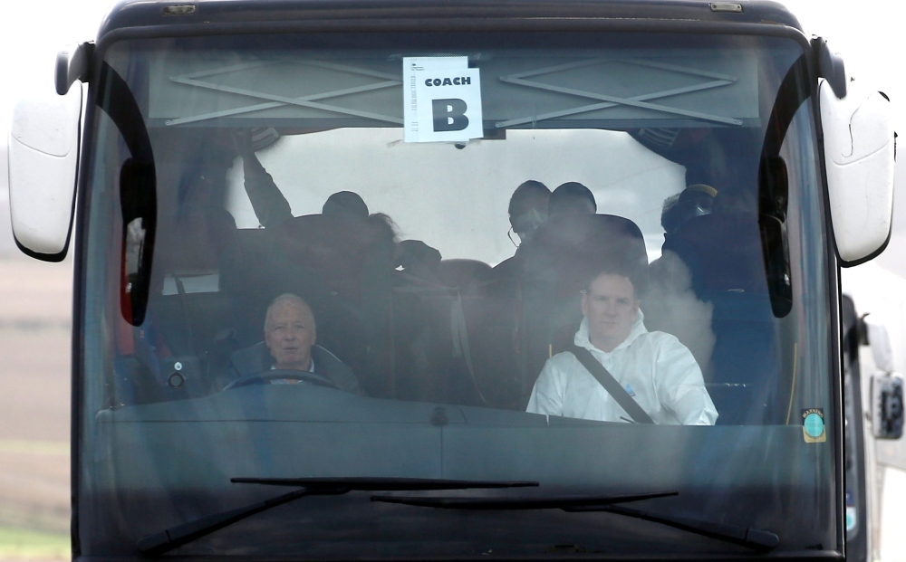 Passengers who have been under quarantine on a coronavirus-stricken cruise ship off the coast of Japan, the Diamond Princess, are seen wearing face masks as they leave RAF Boscombe Down in Amesbury, Britain, February 22, 2020. REUTERS/Henry Nicholls