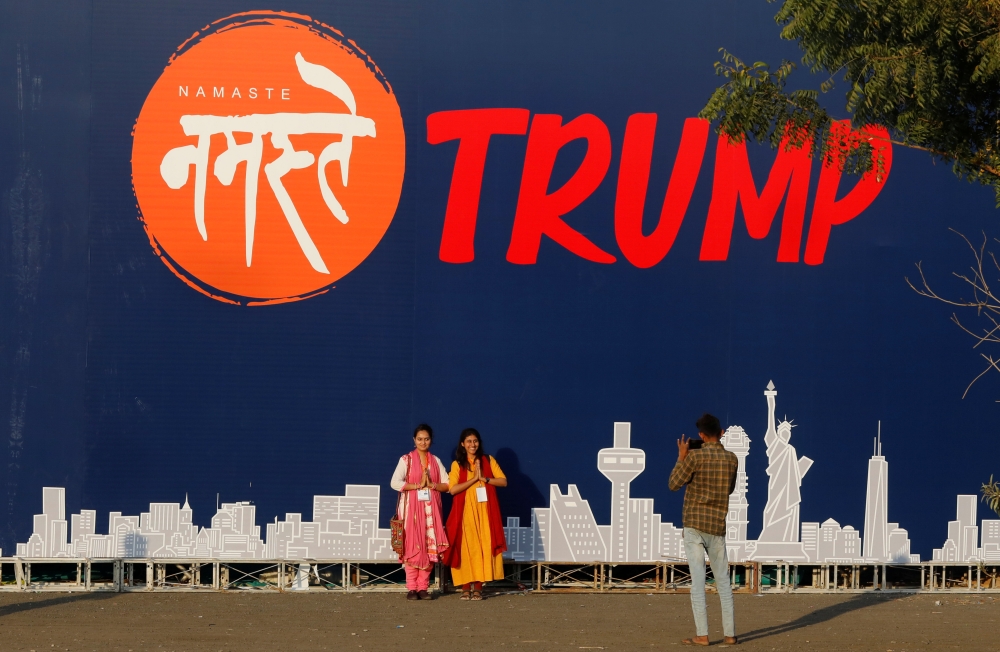 People pose for a picture in front of a hoarding of the 