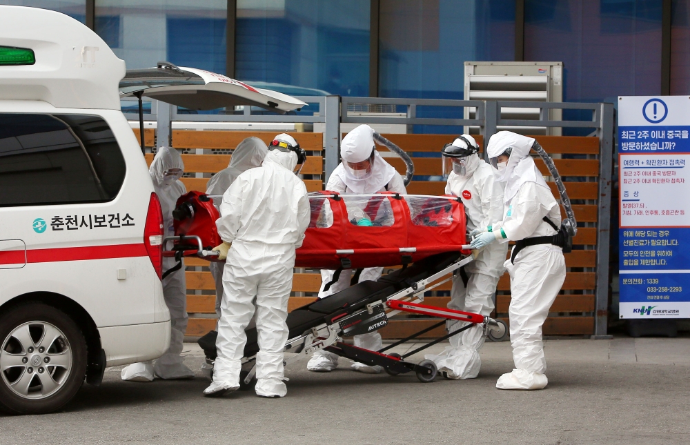 A confirmed coronavirus patient is wheeled to a hospital at Chuncheon, South Korea, February 22, 2020. Yonhap via REUTERS