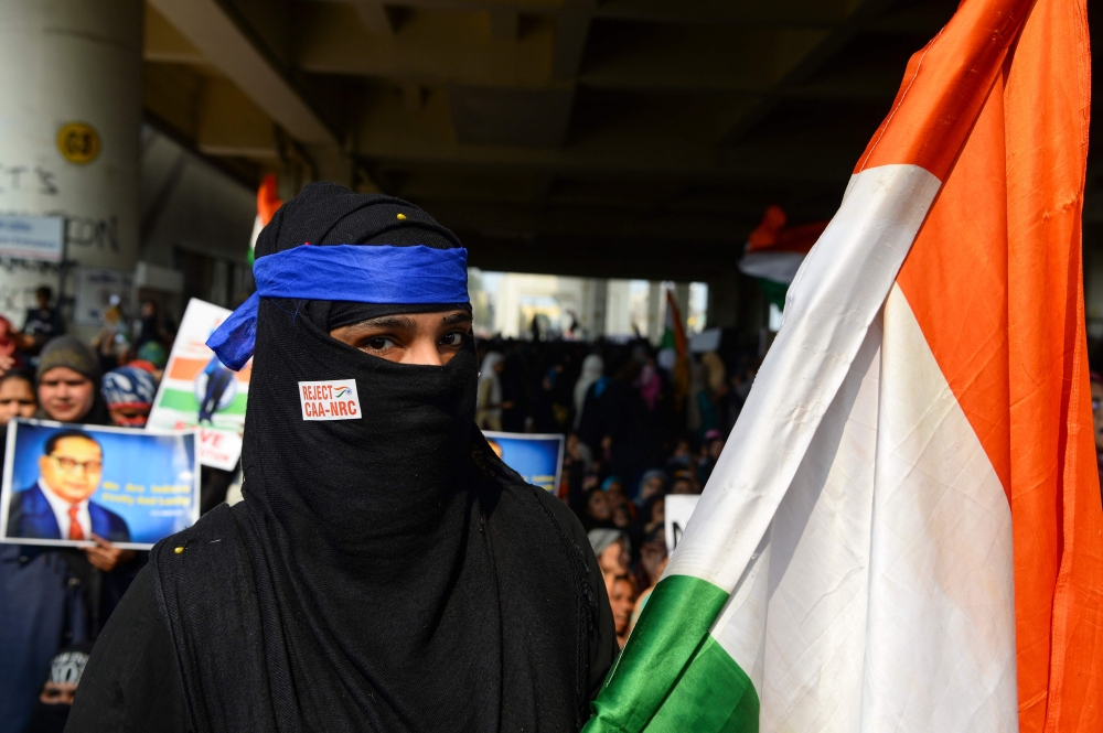 A demonstrator holds an Indian national flag during a protest against the Indian government's Citizenship Amendment Act (CAA) and the National Register of Citizens (NRC) at Jaffrabad area in New Delhi on February 23, 2020. AFP / Sajjad Hussain
 