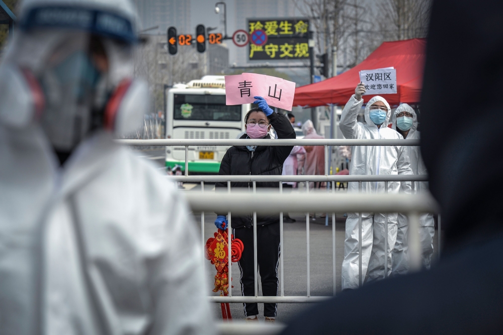 This photo taken on February 22, 2020 shows a woman welcoming people who have recovered from the COVID-19 coronavirus infection as they are discharged from the hospital in Wuhan in China's central Hubei province. China OUT / AFP / STR