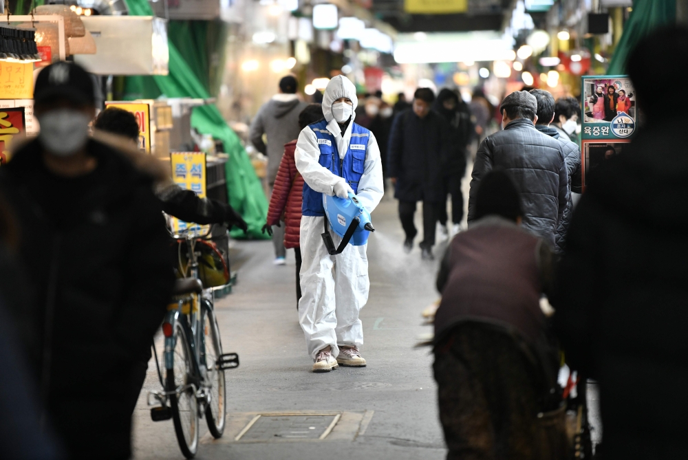 A worker from the Korea Pest Control Association, wearing protective gear, sprays disinfectant to help prevent the spread of the COVID-19 novel coronavirus at a market in Seoul on February 24, 2020. / AFP / Jung Yeon-je 