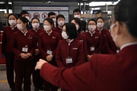 Air China staff position themselves to take a group photo after putting smiley face stickers on their masks, worn as a preventive measure against the  coronavirus on February 24, 2020.(AFP / GREG BAKER)