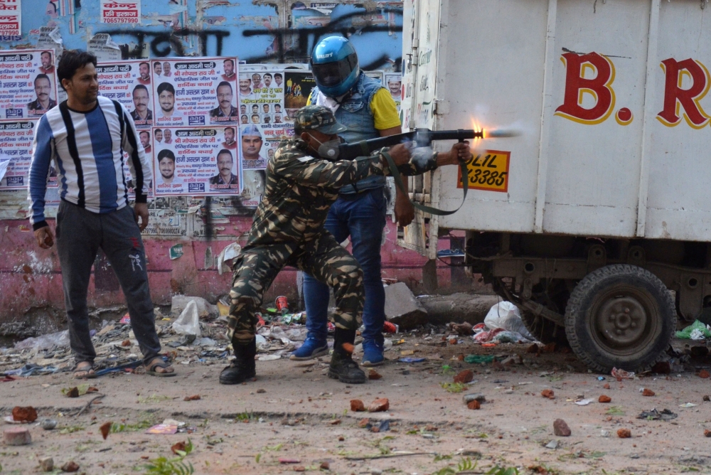 A police officer fires a tear gas shell to disperse crowds after a clash between people supporting a new citizenship law and those opposing the law, in Maujpur area of New Delhi, India, February 23, 2020. (REUTERS/Akash Jain)