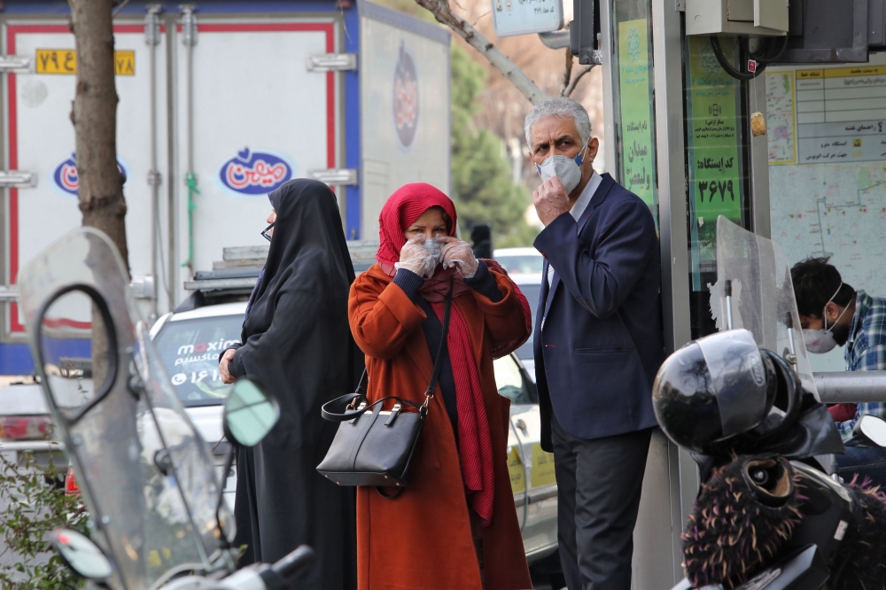 People wearing protective masks wait along the side of a street in the Iranian capital Tehran on February 24, 2020.   AFP / ATTA KENARE
