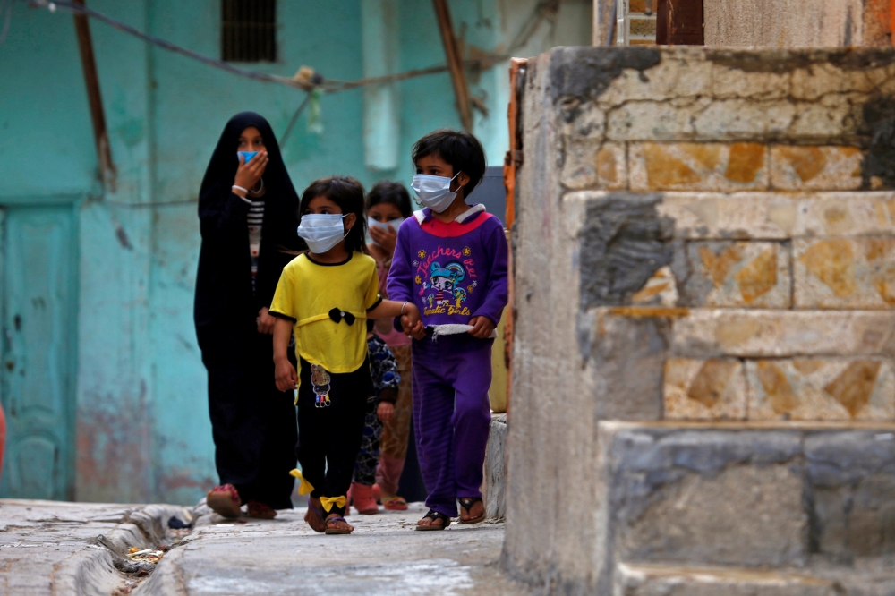 Iraqi children wear protective masks as they walk near a religious school where the first coronavirus case was detected, following the outbreak of the new coronavirus, in the holy city of Najaf, Iraq February 24, 2020. Reuters/Alaa al-Marjani