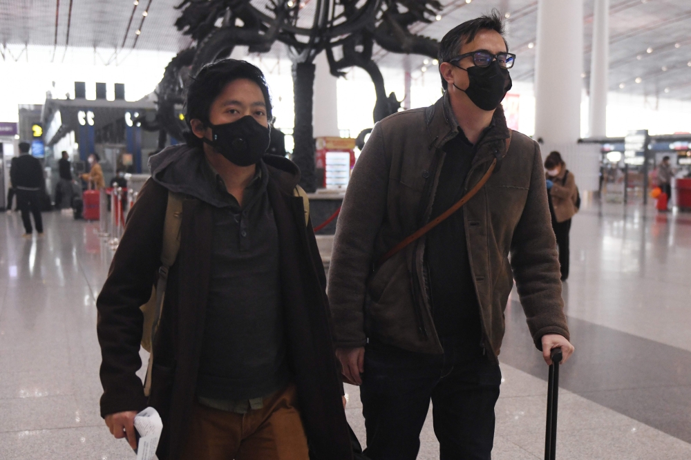 Wall Street Journal reporters Josh Chin (R) and Philip Wen walk through Beijing Capital Airport before their departure on February 24, 2020. AFP / Greg Baker 