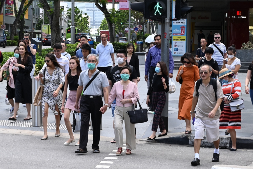  People, some wearing a protective facemask amid fears about the spread of the COVID-19 novel coronavirus, crosses the road in Singapore on February 26, 2020. (Photo by Roslan RAHMAN / AFP) 