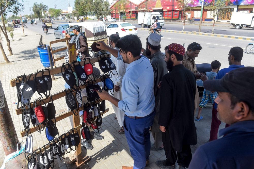  Residents buy facemasks from a roadside vendor along a street in Karachi on February 27, 2020 as Pakistan has detected its first two cases of novel coronavirus./ AFP / Asif HASSAN