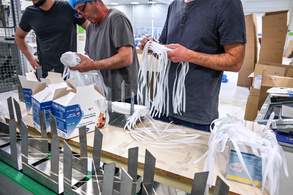 Employees pack respiratory protective face masks on an assembly line at the Valmy manufacturer plant in Mably, central France, on February 28, 2020, amid the spread of coronavirus.  AFP / Philippe Desmazes 