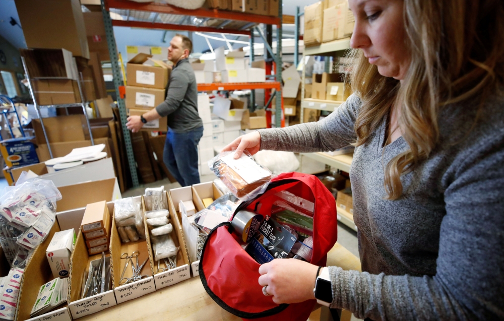 Kristen Curley, owner of Nitro-Pac, puts items into a backpack as part of personal protection and survival equipment kits ordered by customers preparing against novel coronavirus, at Nitro-Pak in Midway, Utah, February 27, 2020. Reuters/George Frey