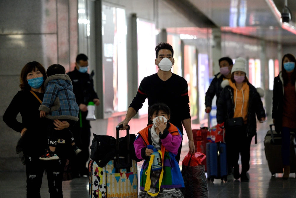 This photo taken on February 28, 2020 shows passengers wearing face masks arriving at Wenzhou railway station in Wenzhou. The National Health Commission on March 1 reported 573 new infections, bringing the total number of cases in mainland China to 79,824