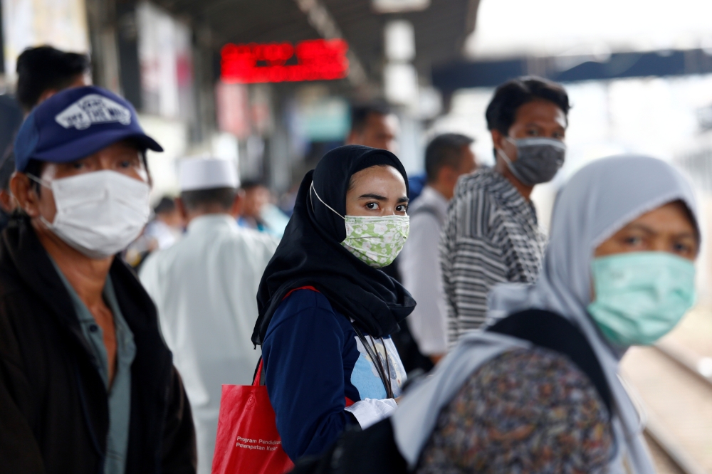 FILE PHOTO: People with surgical masks look on at station Tanah Abang, following the outbreak of the coronavirus in China, in Jakarta, Indonesia February 13, 2020. REUTERS/Ajeng Dinar Ulfiana/File Photo