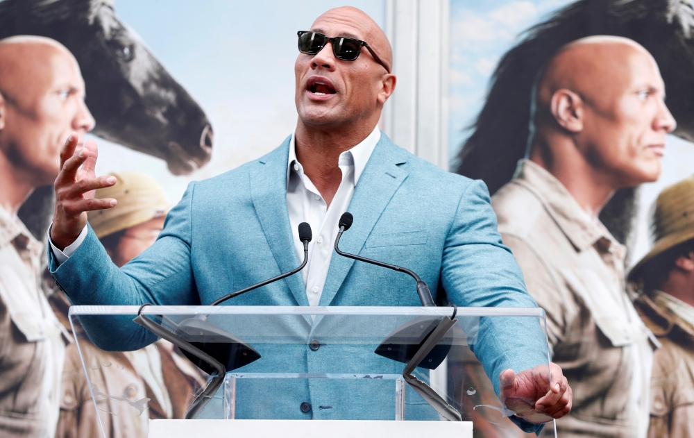  FILE PHOTO: Actor Dwayne Johnson speaks during a ceremony for actor Kevin Hart to place his handprints and footprints in cement in the forecourt of the TCL Chinese theatre in Los Angeles, California, U.S., December 10, 2019. REUTERS/Mario Anzuoni/File Ph