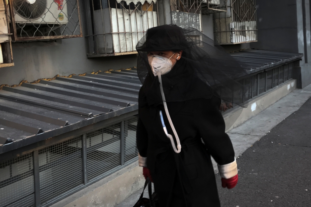 A woman wears a face mask as she walks in a street in Beijing as the country is hit by an outbreak of the novel coronavirus, China, March 4, 2020. REUTERS/Thomas Peter
