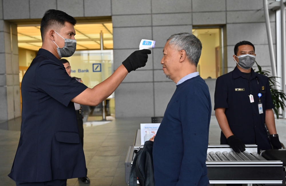 An Indonesian security personal checks the body temperature of a man to entering a building in Jakarta on March 5, 2020. AFP / ADEK BERRY