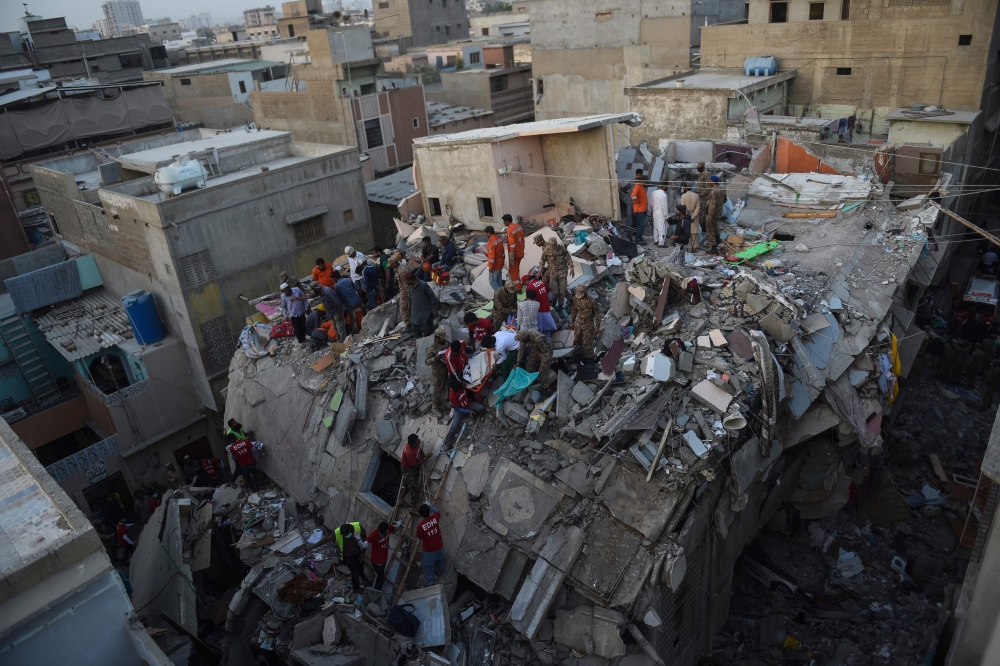  Pakistani volunteer moves the body of a victim from the rubble of a collapsed five-storey residential building in Karachi on March 5, 2020. / AFP / Asif HASSAN