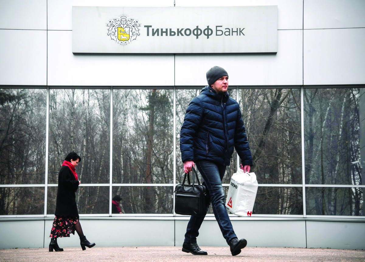 People walk past the logo of the Tinkoff Bank headquarters in Moscow on March 6, 2020.  AFP / Alexander Nemenov
