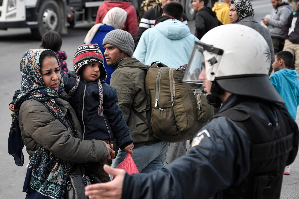 A woman and a child are blocked by policemen as police push back migrants back from Moria camp who gathered near the port of Mytilene on the island of Lesbos, hoping to get a ferry to Athens on March 4, 2020. AFP / Louisa Gouliamaki
 