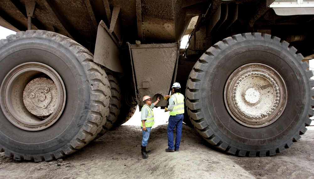 Two Colombian miners inspect a mining truck in the Cerrejon coal mine in Guajira province, May 24, 2007. Reuters/Jose Miguel Gomez